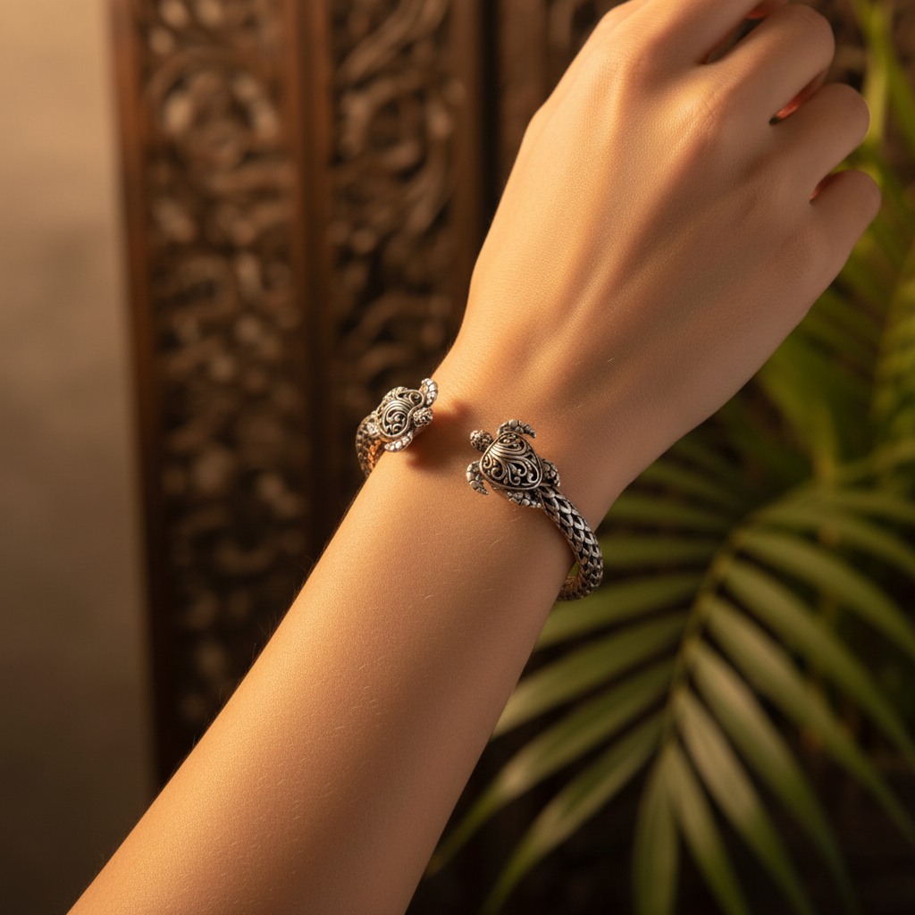 Bracciale Penyu Balinesia indossato al polso con sfondo porta intagliata balinese e foglia di palma, bangle aperto in argento 925 ossidato con tartaruga scolpita in primo piano