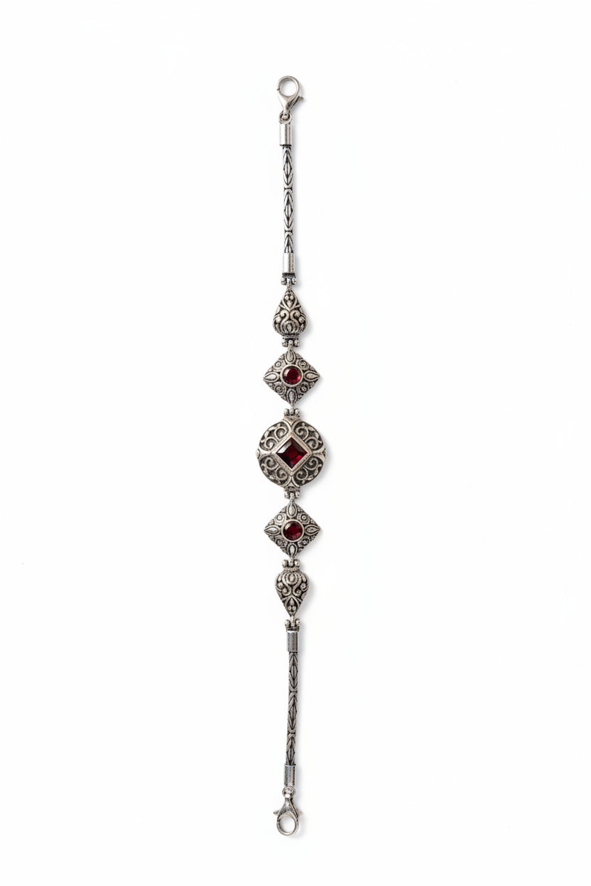 Bracciale Pati Balinesia disteso – vista completa con catena intrecciata, elementi a filigrana con granati rossi e chiusura – Argento 925 ossidato, Collezione Viaggio a Celuk