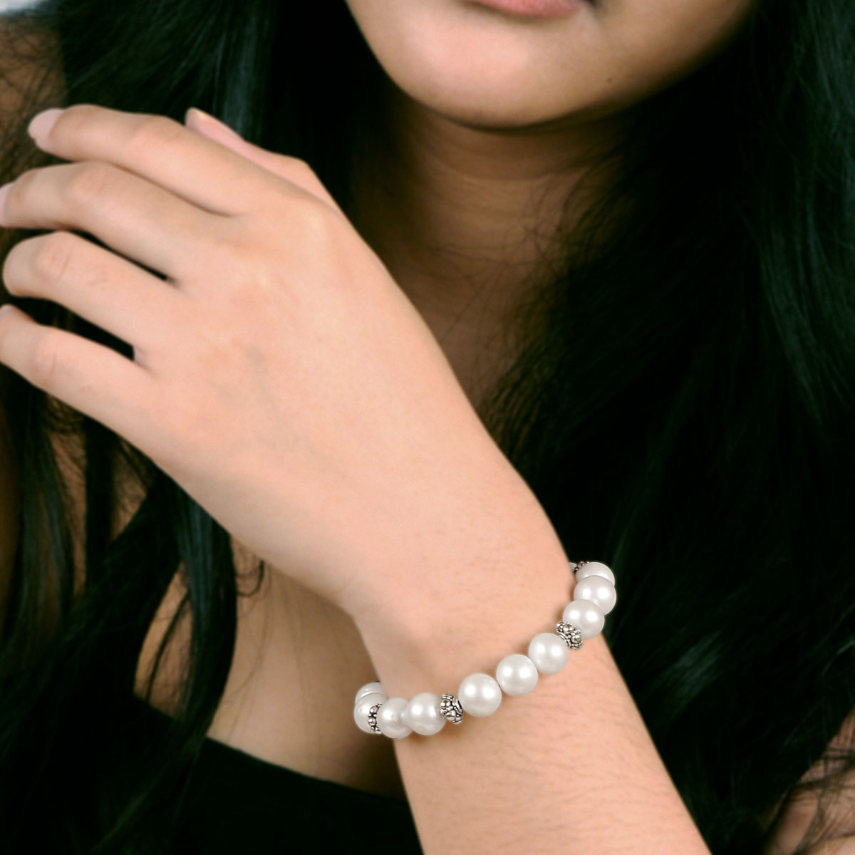 Bracciale Mutiara Balinesia indossato da modella con top scuro, perle di acqua dolce tonde bianche con separatori a filigrana in argento 925 ossidato al polso, Collezione Oceano e Sabbia