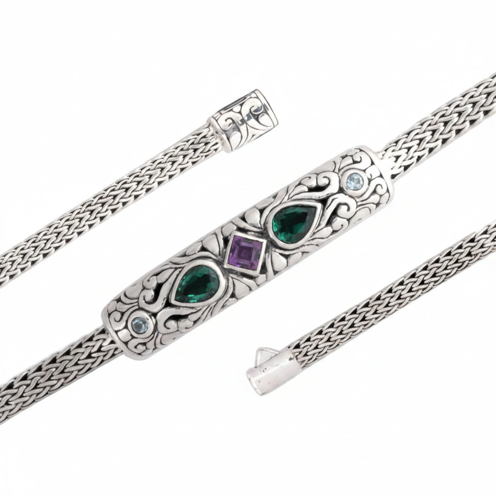 Bracciale Tulang Naga Balinesia su sfondo bianco, trittico – barra centrale con smeraldi e ametista (in alto), dettaglio catena tulang naga e terminale (in basso sinistra), chiusura a scatto con incisioni balinesi (in basso destra)