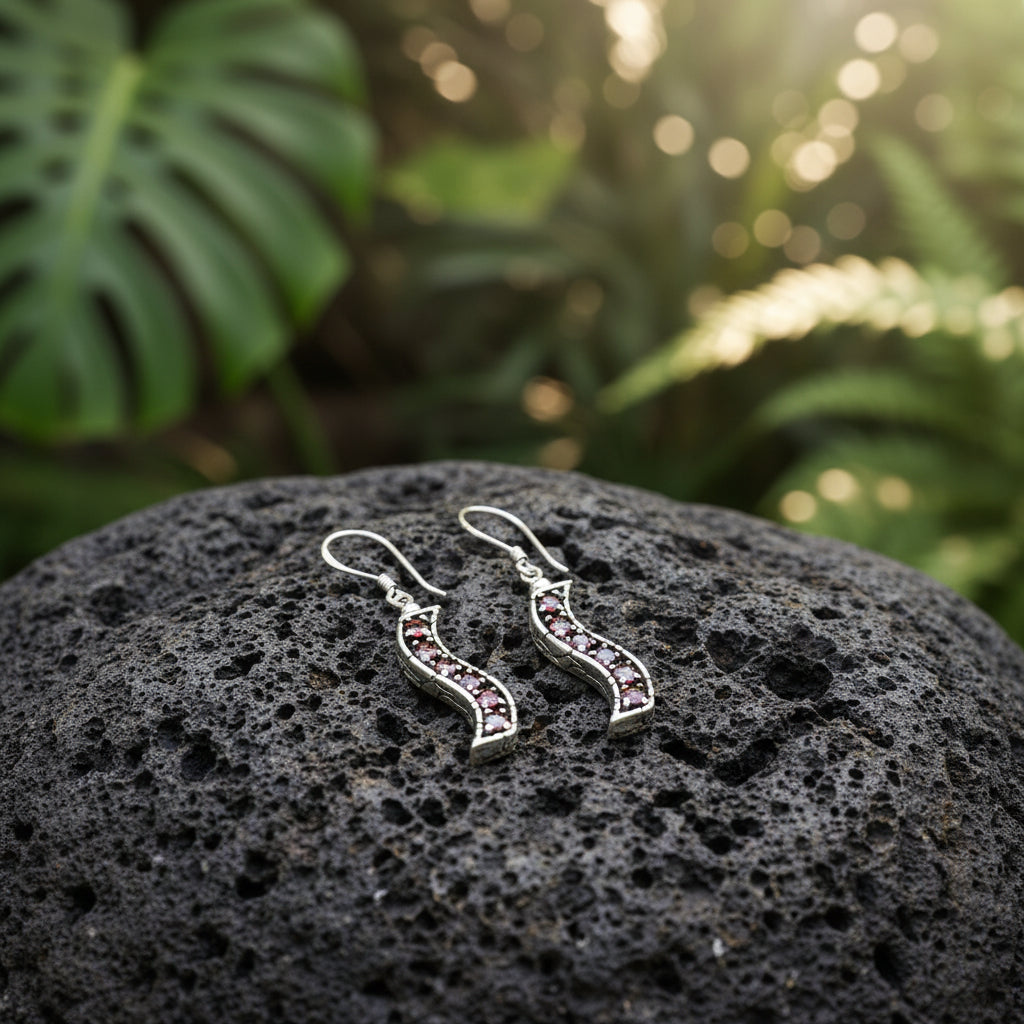 Coppia di Orecchini Buaya Merah posata su pietra lavica balinese con foglie tropicali, argento 925 ossidato con granati naturali rossi in luce naturale – Balinesia