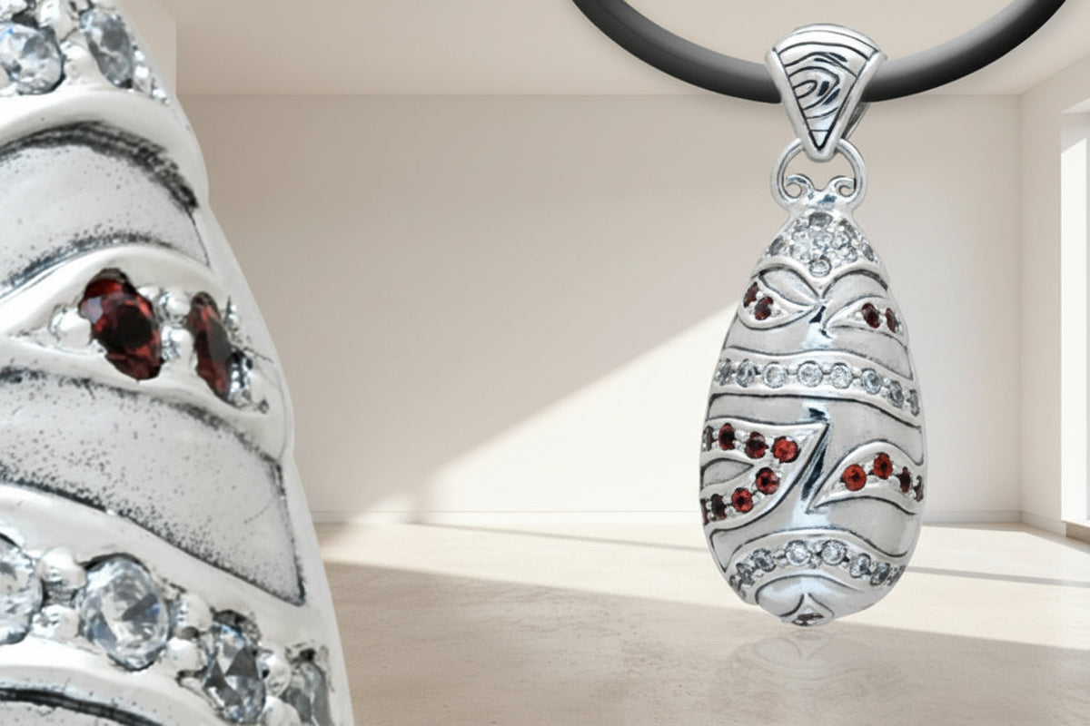 Ciondolo Hujian in argento 925 ossidato con granati rossi e zirconi bianchi, forma ovale bombata con fasce diagonali cesellate – Collezione Essenza di Ubud, Balinesia