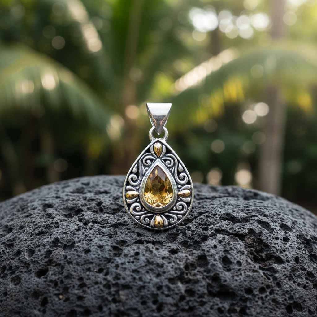 Ciondolo Embun Balinesia su roccia vulcanica nera con sfondo giungla tropicale bokeh e luce dorata, citrino naturale taglio pera e dettagli in oro in primo piano