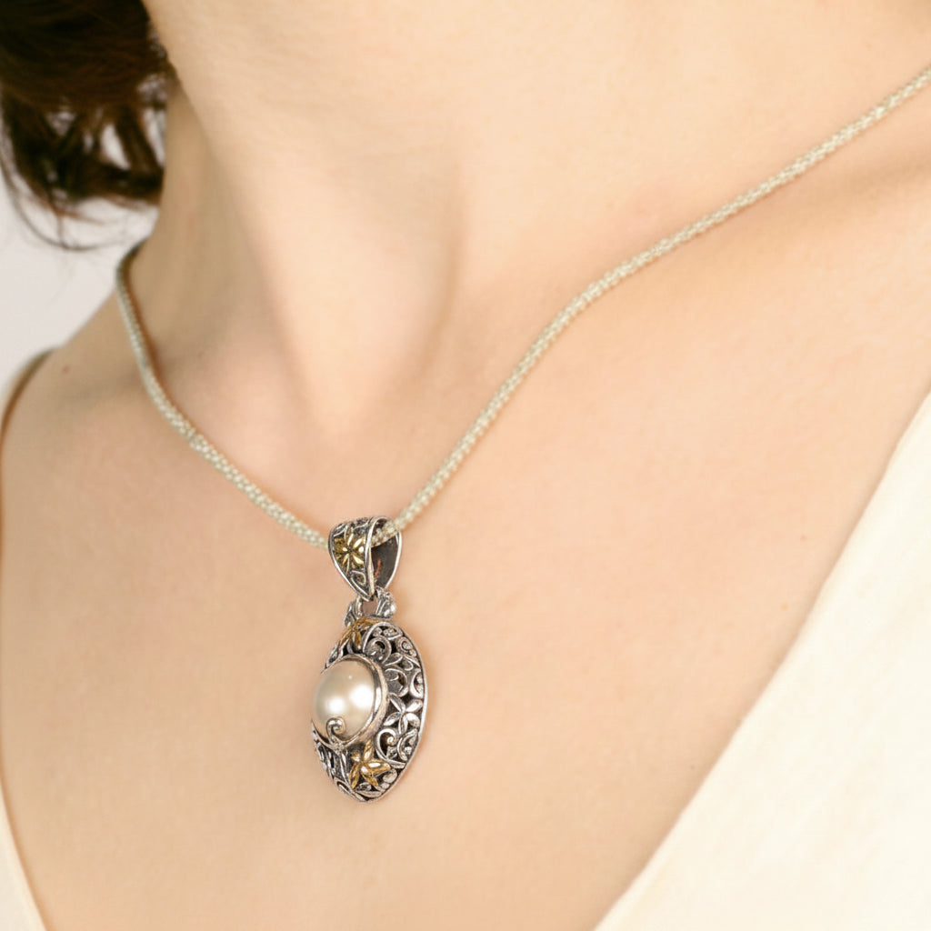 Retro Ciondolo Lovina Balinesia su sfondo bianco con motivi a spirale traforati in argento 925 ossidato, perla Mabé in trasparenza e punzoni 925 e 18k incisi