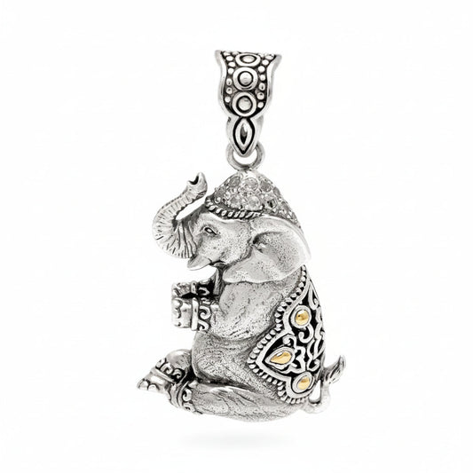 Ciondolo Gajah Balinesia, vista 3/4 su sfondo bianco con elefante seduto in argento 925 ossidato, topazi bianchi naturali sul copricapo a pavé e dettagli in oro 18k sulla gualdrappa