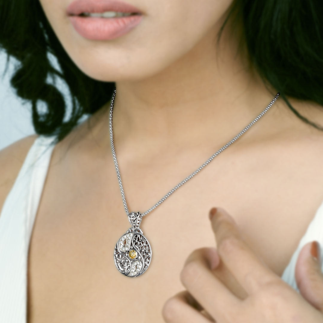 Ciondolo Yin Yang Balinesia indossato su modella con top bianco, catena veneziana sottile in argento, ciondolo circolare traforato con zirconi bianchi e dettaglio in oro 18k in primo piano