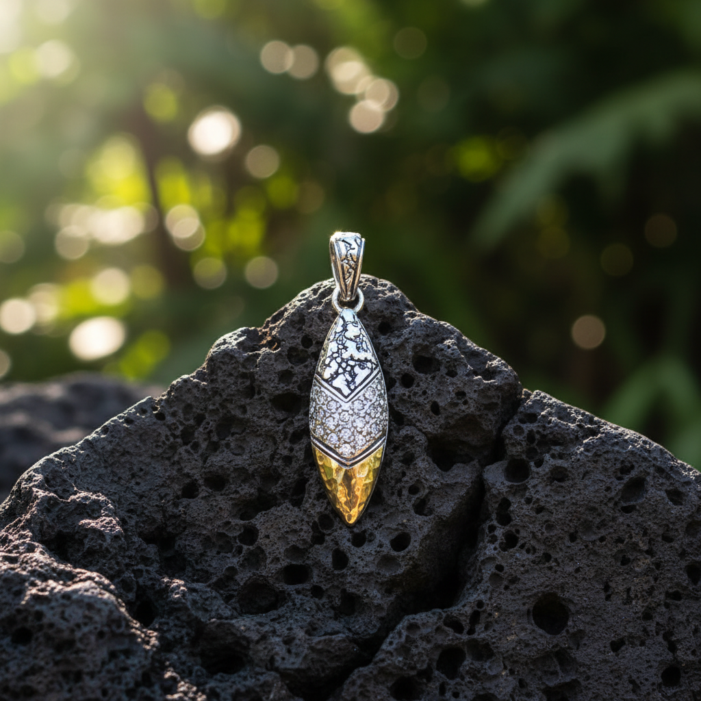 Ciondolo Daun Gunung Balinesia, vista frontale su sfondo bianco con White Topaz bianchi brillanti a pavé, punta conica in oro 18k martellato e gancio ovale in argento 925 ossidato