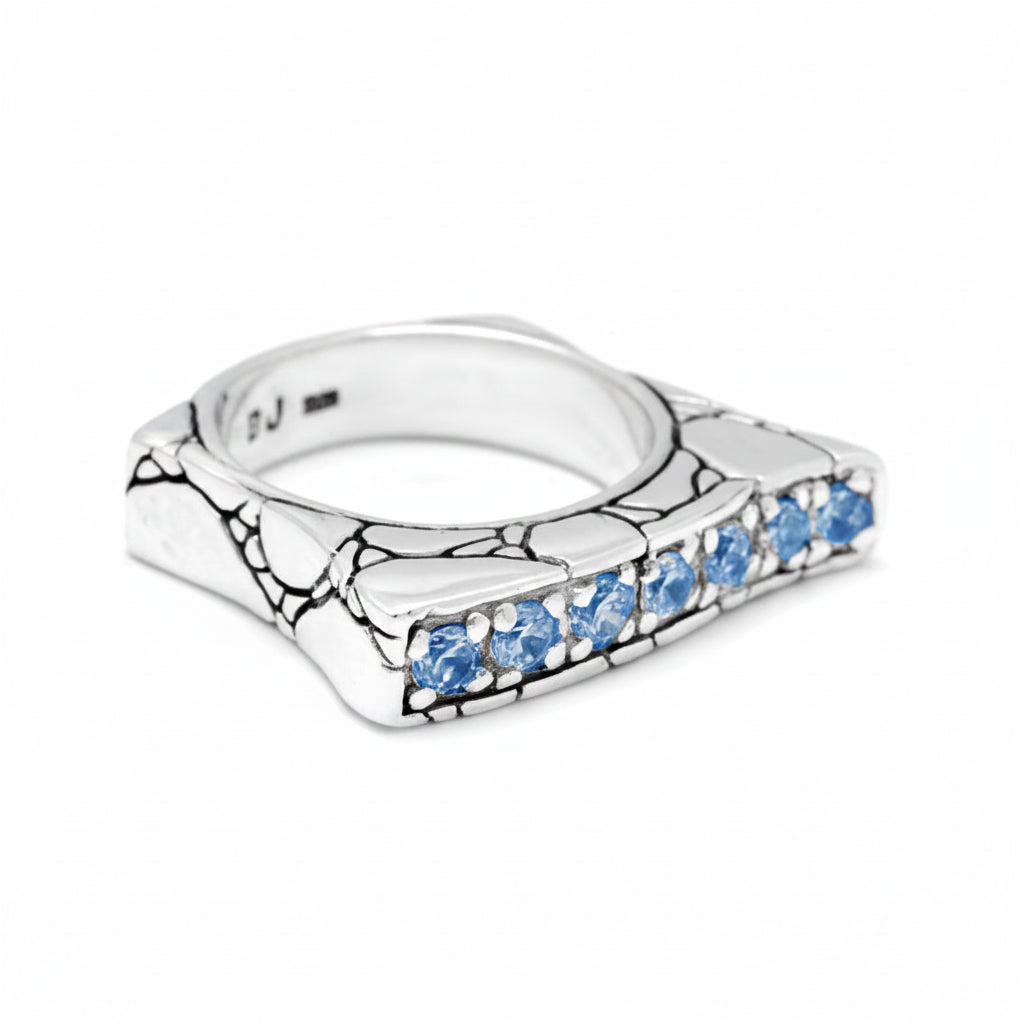 Anello Batu Biru della Collezione Crocodile Balinesia posato su pietra lavica, sfondo giungla tropicale