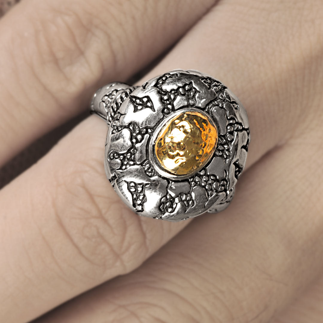 Anello Batu Api Balinesia, doppia vista frontale e laterale su sfondo bianco, castone ovale oro 18K e fascia bombata in argento ossidato