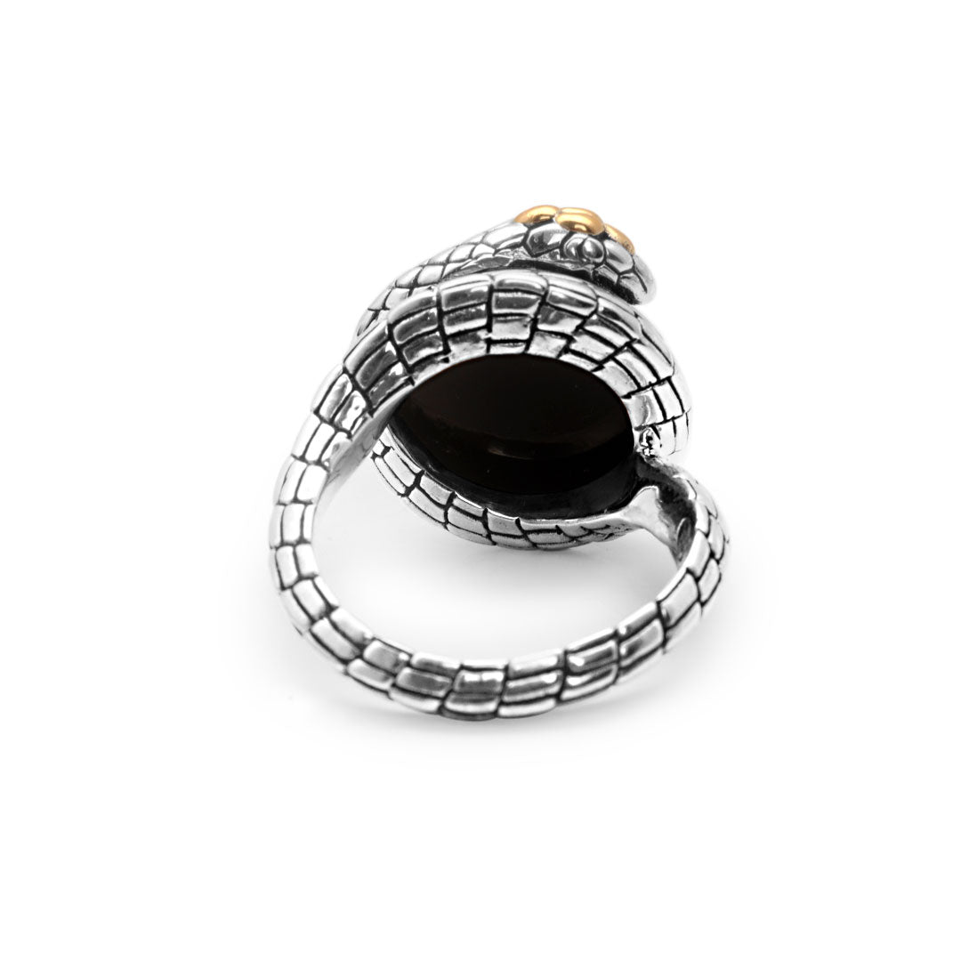 Anello Cobra Onyx Balinesia, vista dall'alto 3/4 su sfondo bianco, testa serpente scolpita con occhio in oro su scaglie esagonali, cabochon onice nera e coda avvolgente in argento 925 ossidato