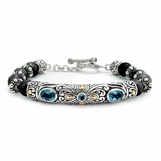 Bracciale Naga in argento 925 con barra a filigrana balinese, topazio blu London, accenti in oro 18K e perle di onice nero — vista frontale su sfondo bianco, Collezione Viaggio a Celuk, Balinesia