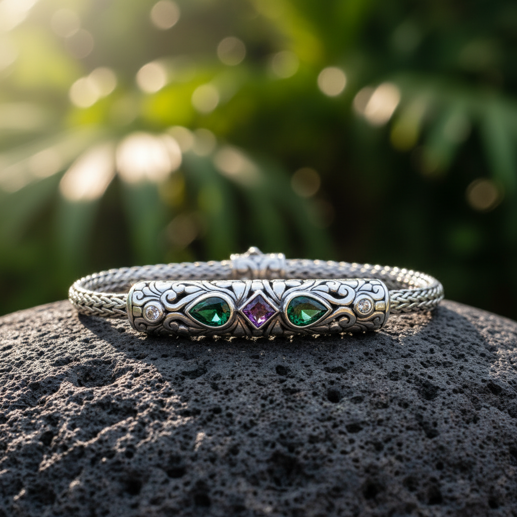 Bracciale Tulang Naga Tre Gemme Balinesia su roccia lavica nera con sfondo giardino tropicale – barra decorata con smeraldi a goccia, ametista princess e topazi bianchi su catena intrecciata in argento 925 ossidato – Collezione Viaggio a Celuk