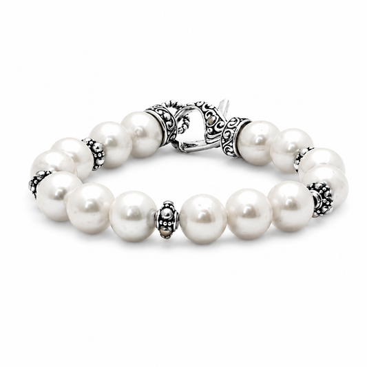 Bracciale Mutiara Balinesia su sfondo bianco, bracciale di perle di acqua dolce tonde con separatori a filigrana granulata in argento 925 ossidato e chiusura lobster decorata con motivi a voluta, Collezione Oceano e Sabbia