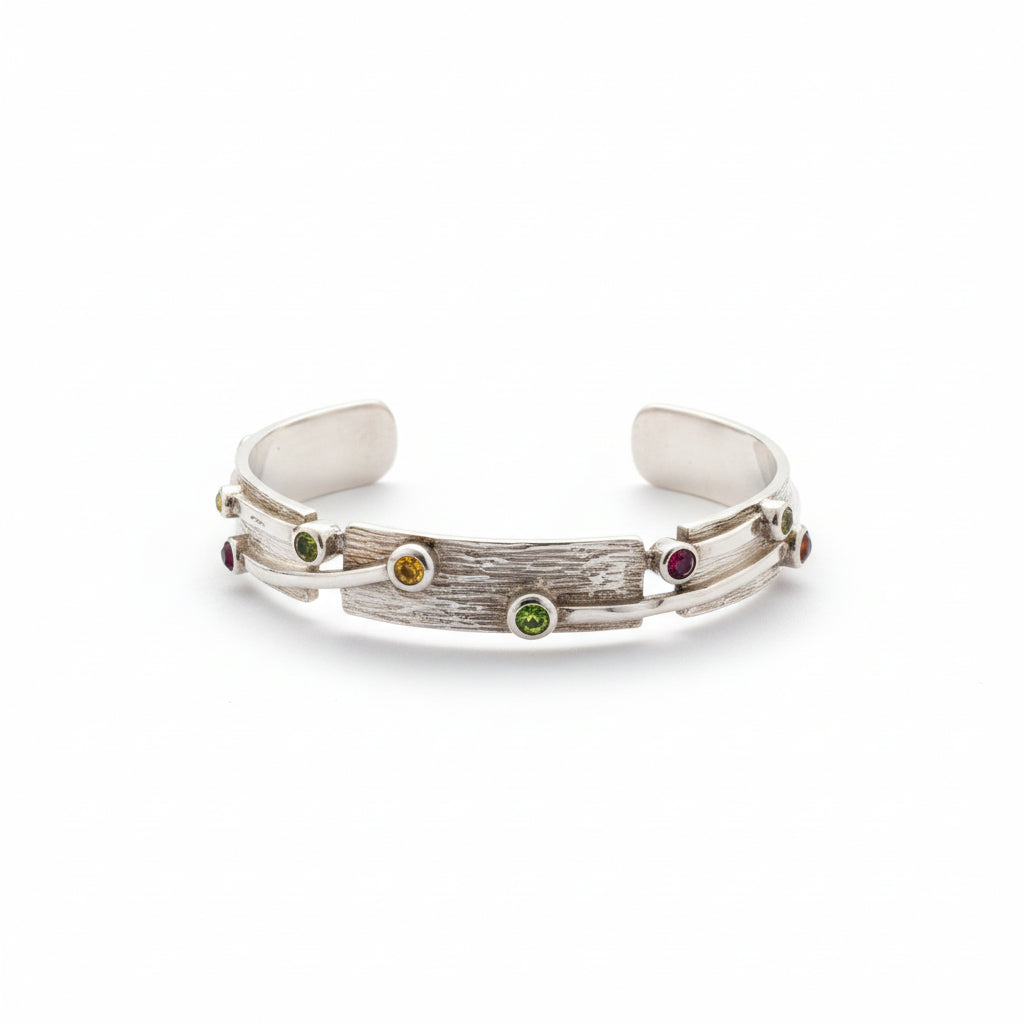 Bracciale Kulit Pohon in argento 925 con texture a corteccia incisa a mano – peridoto verde, citrino giallo e granato rosso incastonati a castone – bangle rigido aperto, Balinesia, Collezione Essenza di Ubud