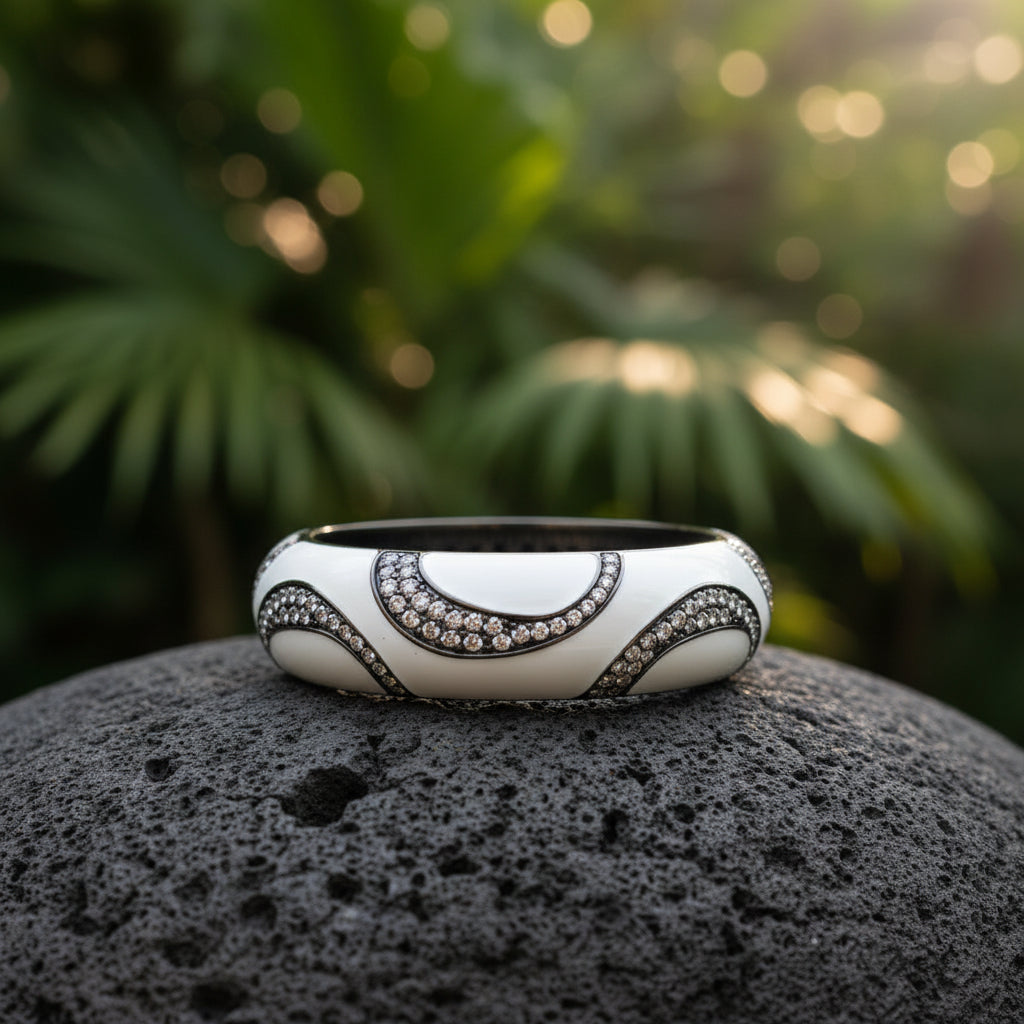 Bracciale bangle Ombak Bianco posato su roccia lavica con sfondo di vegetazione tropicale — Collezione Notte Tropicale, Balinesia