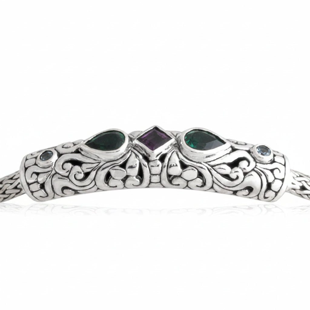 bracciale Tulang Naga Balinesia, dettaglio macro barra centrale su sfondo bianco – incisioni a volute balinesi in argento 925 ossidato con due smeraldi a goccia verde, ametista princess viola al centro e topazi bianchi laterali