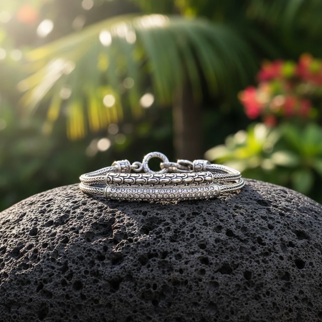 Bracciale Naga Topaz posato su pietra lavica in un giardino tropicale di Bali, doppia catena Sisik Naga con pavé di topazi bianchi naturali, argento 925 – Balinesia