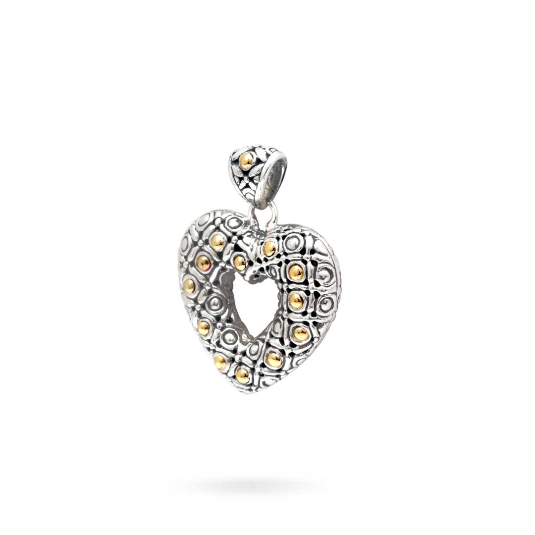 Ciondolo Hati Celuk Balinesia su sfondo bianco, vista laterale-frontale, cuore tridimensionale in argento 925 ossidato con sfere in oro 18K, texture a rilievo balinese, bail a diamante con sfera oro, Collezione Viaggio a Celuk