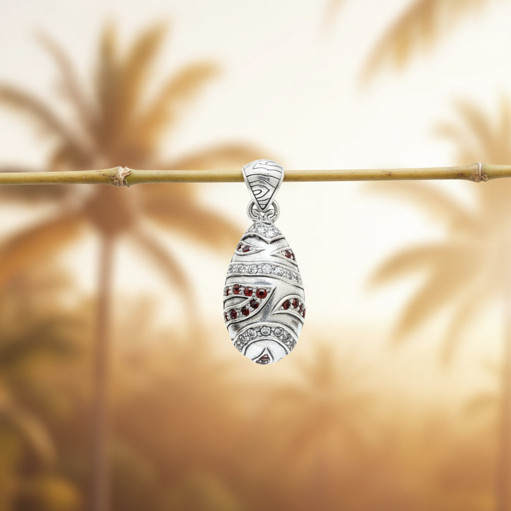 Ciondolo Hujian in argento 925 appeso a un ramoscello di bambù con sfondo di palme tropicali – Granati rossi e zirconi bianchi, artigianato Balinese – Balinesia