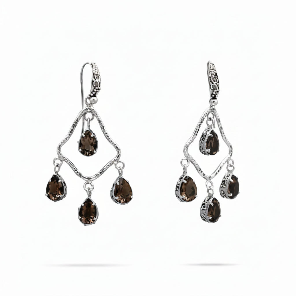 Orecchini Chandelier Quarzo Fumé Balinesia, coppia su sfondo bianco, telaio a rombo in argento 925 ossidato con texture martellata e quattro quarzi fumé naturali pear shape marrone-ambra per orecchino, gancio decorato con volute balinesi, Collezione Essenza di Ubud