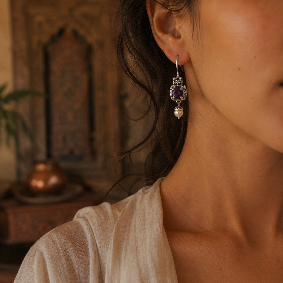 Orecchini Ametista e Perla Collezione Viaggio a Celuk Balinesia indossati da modella, pendenti con ametista viola e perla naturale su castone cesellato in argento 925 ossidato