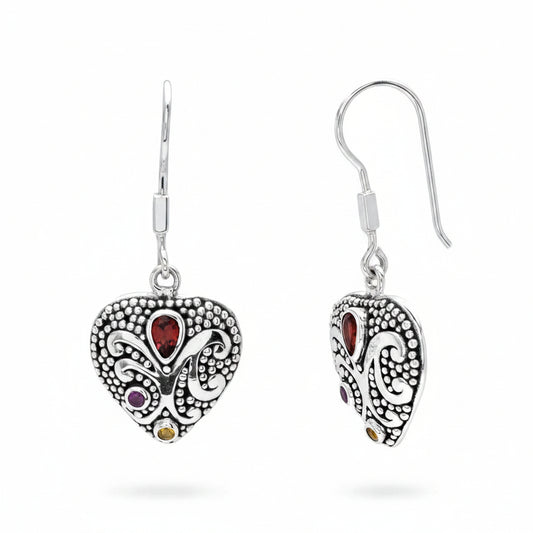 Orecchini Cinta Tiga Warna Balinesia su sfondo bianco – coppia a cuore in argento 925 ossidato con granulazione e volute balinesi, granato rosso pear, ametista viola e citrino giallo – Collezione Viaggio a Celuk