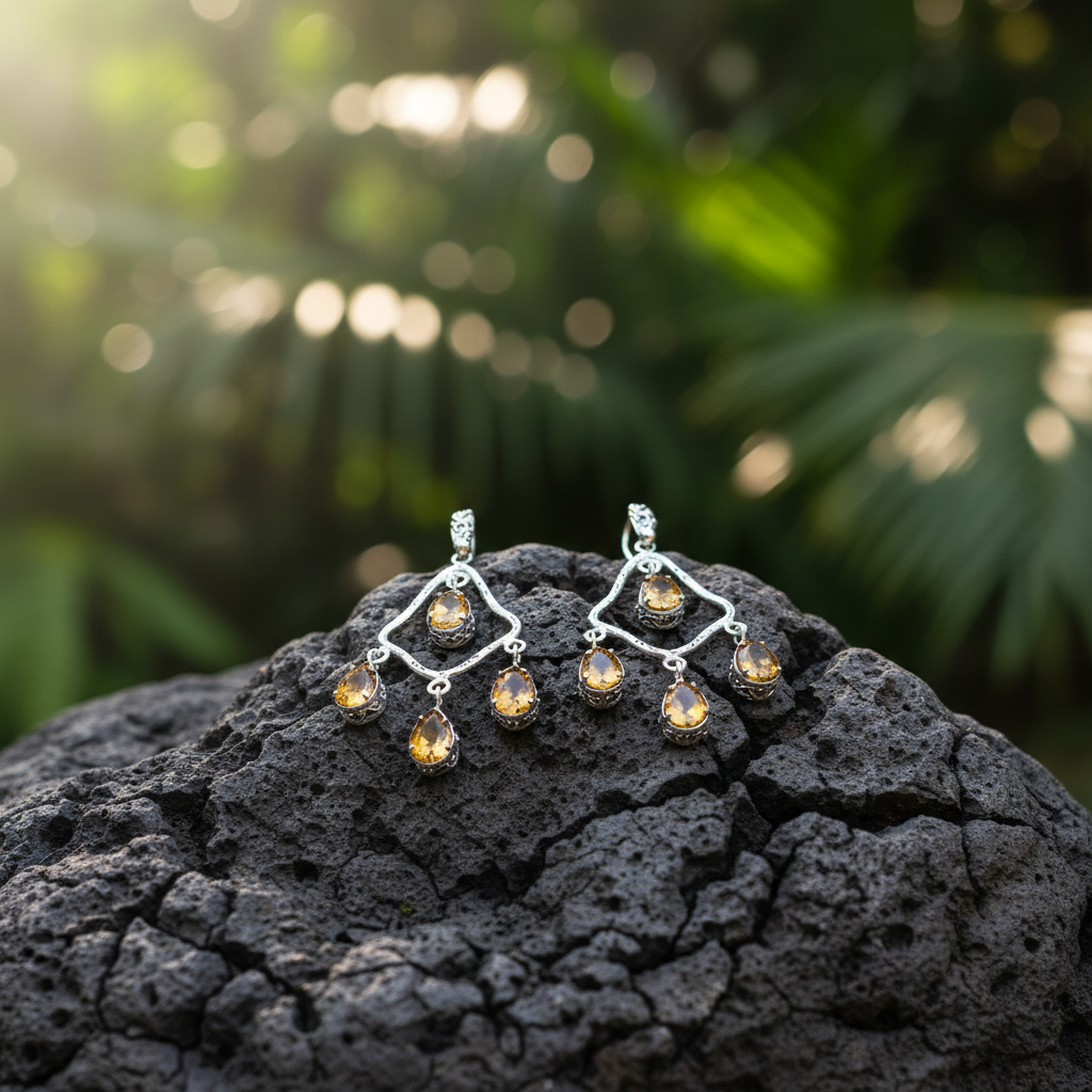 Orecchini Chandelier Citrino Balinesia su roccia lavica nera con sfondo giungla balinese illuminata dal sole, coppia con struttura a rombo in argento 925 brunito e otto citrini naturali pear shape giallo-ambra, Collezione Essenza di Ubud