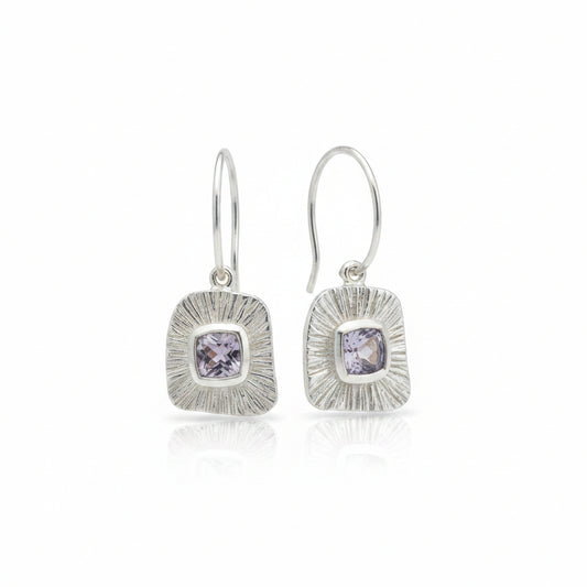 Orecchini Bulan Balinesia, coppia su sfondo bianco con pendenti in argento 925, montatura rettangolare con texture a raggi solari e ametista naturale taglio cuscino viola lavanda, gancio ear-wire in argento