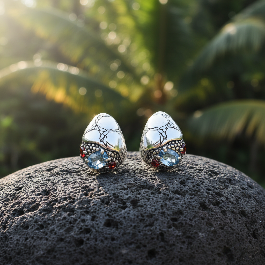 Coppia di Orecchini Goccia Sinar Clip posata su pietra lavica balinese, argento 925 ossidato con texture Crocodile e pietre naturali topazio sky blue e granato – Balinesia