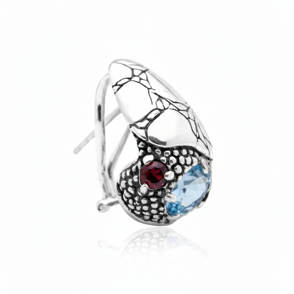 Orecchini Goccia Sinar Clip in argento 925 ossidato, vista laterale sinistra su sfondo bianco, texture Crocodile nella metà superiore e granulazione balinese con granato e topazio sky blue – Balinesia