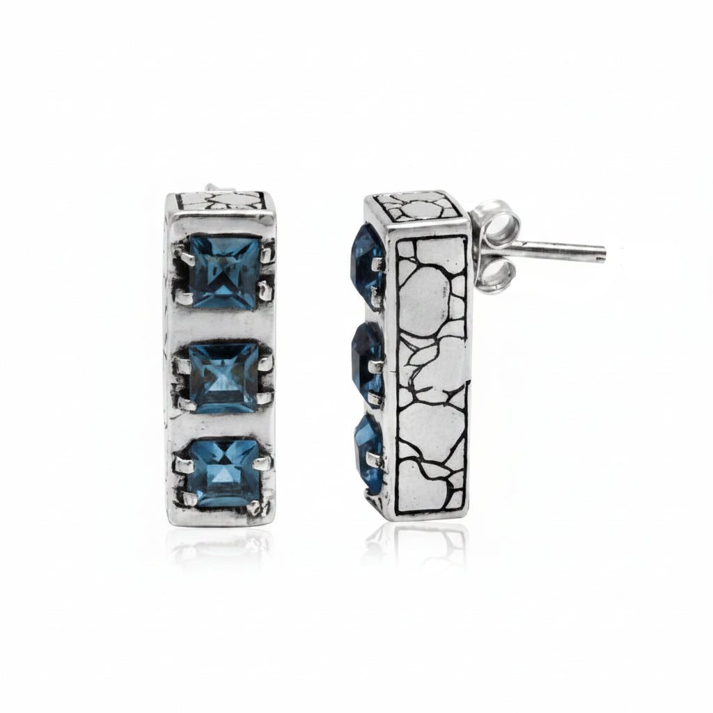 Orecchini Sinar Sky Blue Topaz in argento 925 ossidato, barra rettangolare verticale con 3 topazi blu quadrati a griffe e texture Crocodile, vista frontale e laterale su sfondo bianco – Balinesia