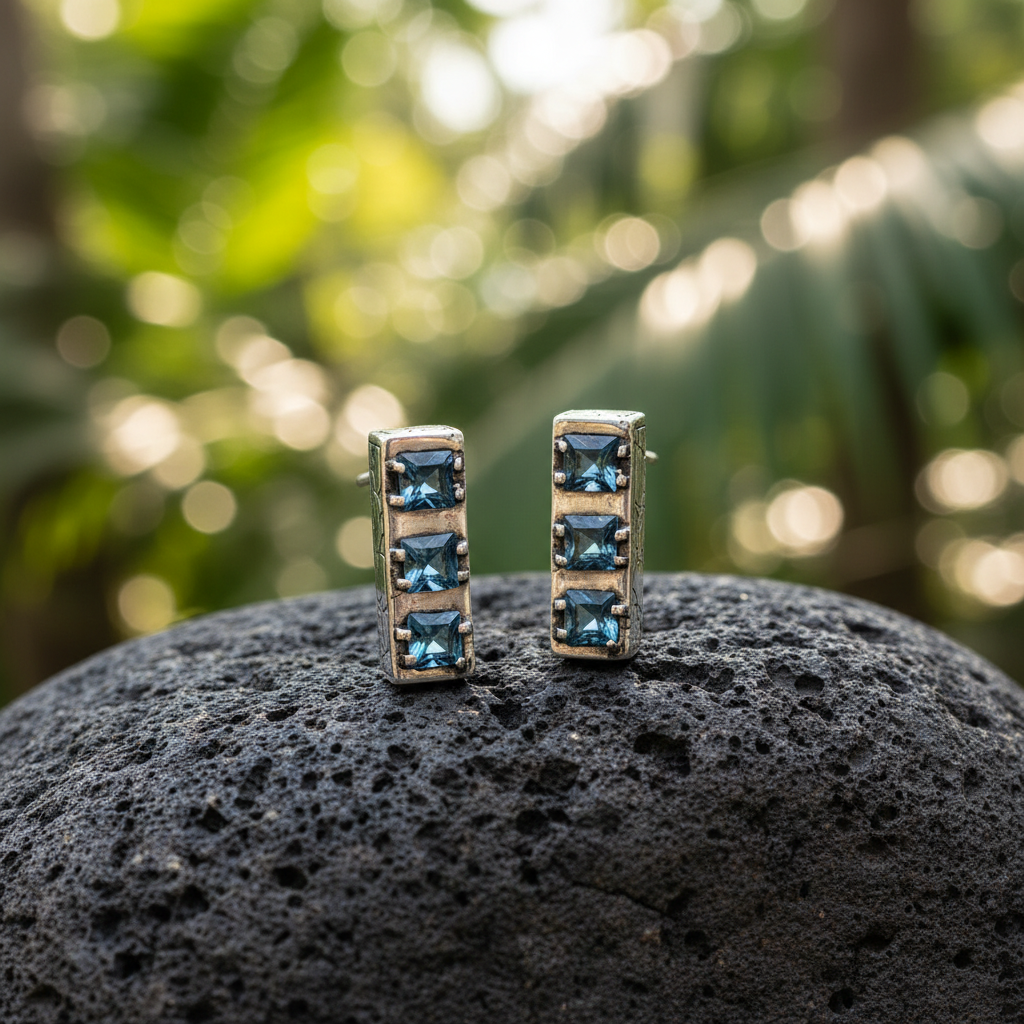 Orecchini Sinar Sky Blue Topaz posati su pietra lavica nella foresta tropicale di Bali, argento 925 ossidato con texture Crocodile e 3 topazi blu quadrati per orecchino – Balinesia